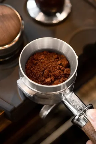 Vòng đong nhôm gắn trên tay cầm espresso chứa đầy bột cà phê vừa xay