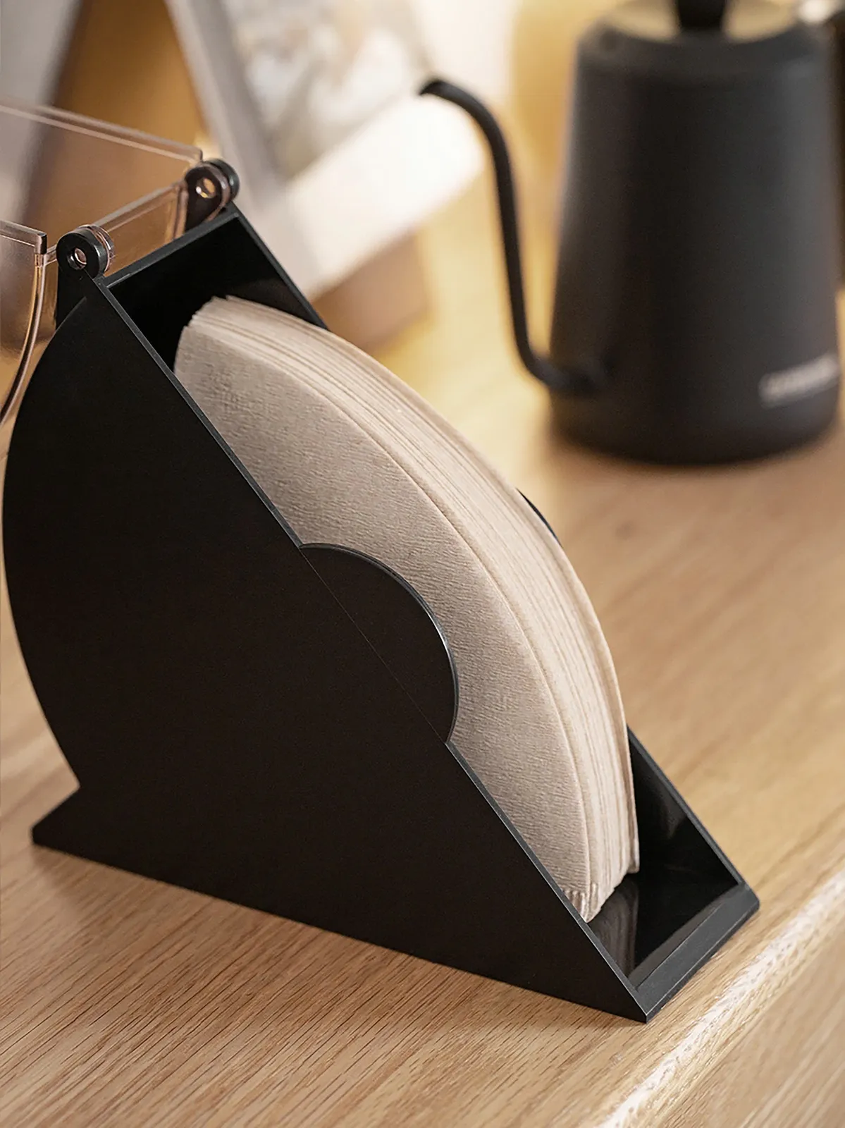 Giấy lọc nhô ra mép hộp đựng giấy lọc CAFE DE KONA đặt trên bàn gỗ
