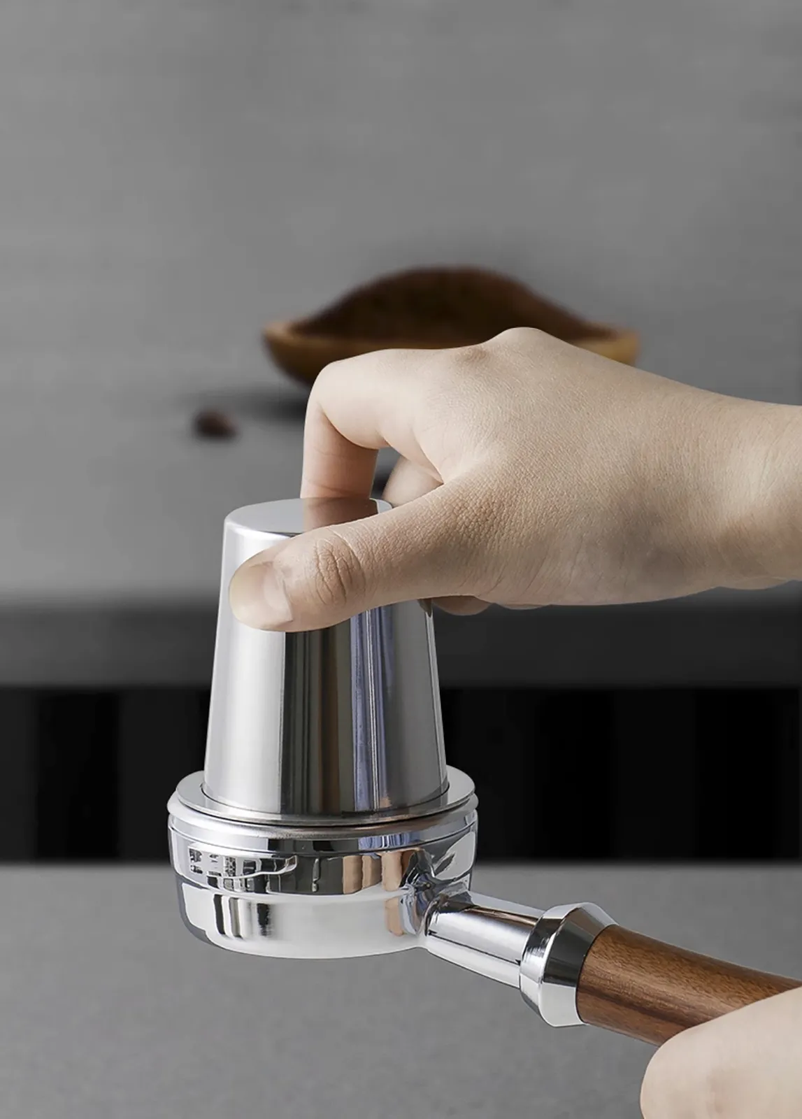 Tay giữ ly dosing cup úp ngược vào tay pha để trút bột cà phê xuống giỏ lọc