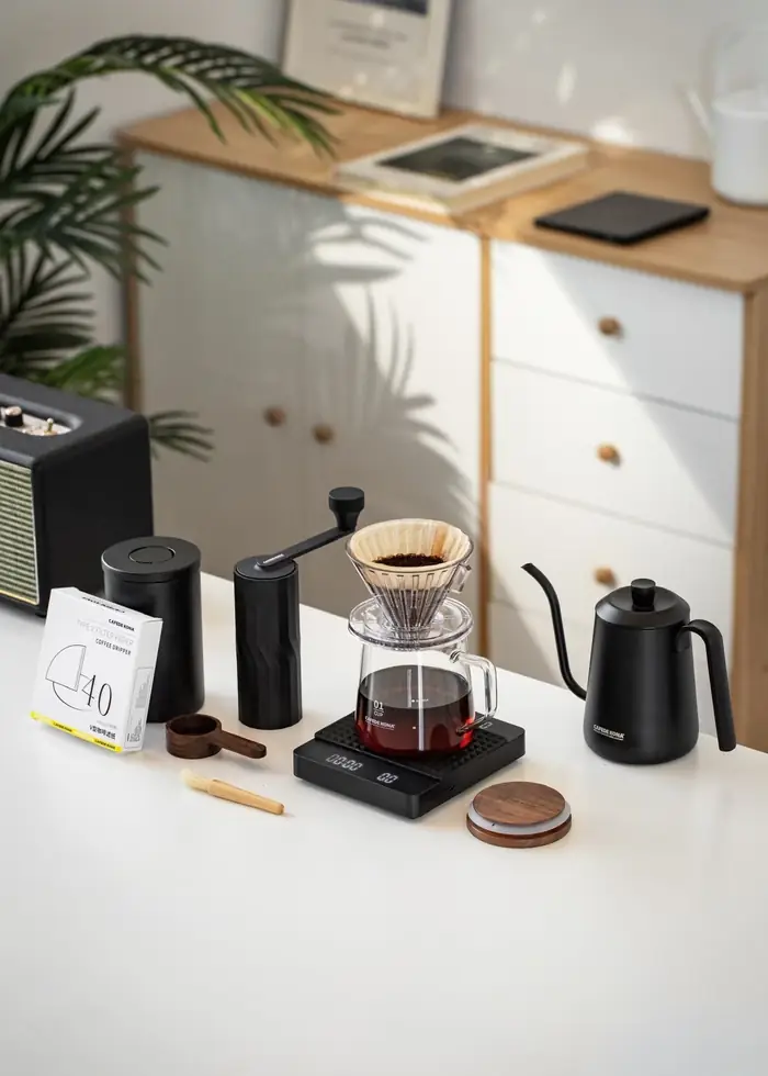Bộ dụng cụ pha cà phê V60 CAFE DE KONA gồm cối xay, cân, phễu, bình, ấm cổ ngỗng bày trên bàn làm quà tặng
