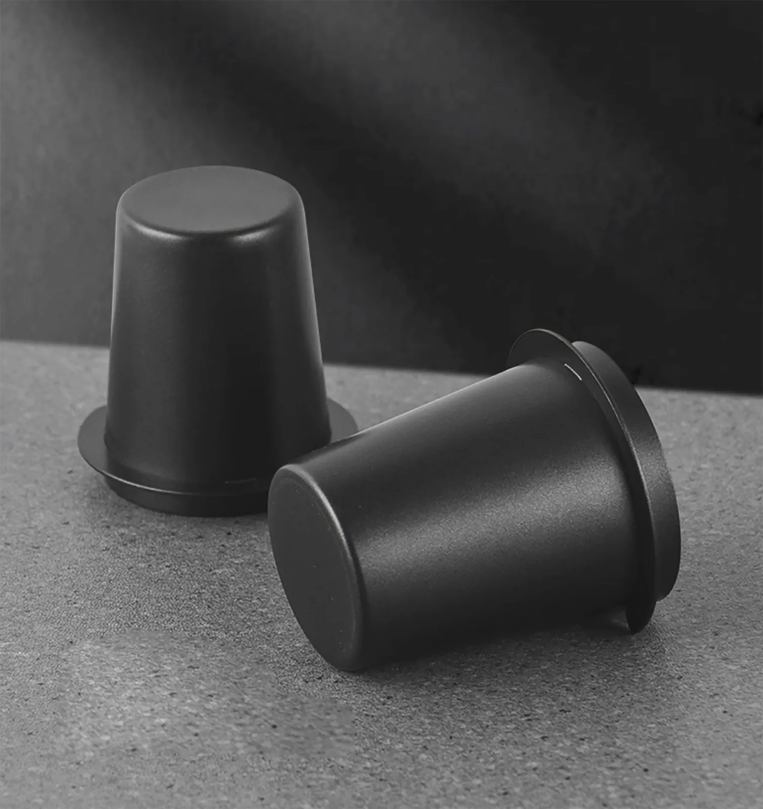 Hai ly dosing cup CK5840 màu đen nằm trên nền tối làm nổi bề mặt nhám