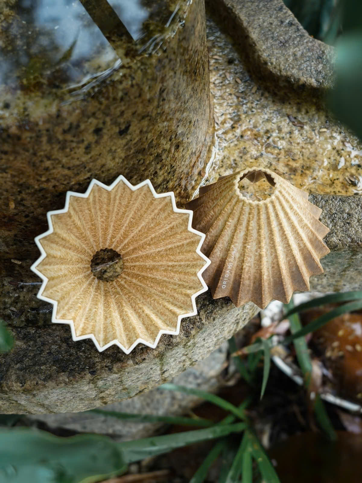 Hai phễu Origami Dripper S Rinko đặt trên tảng đá phủ rêu, một chiếc nhìn từ trên xuống một chiếc nghiêng