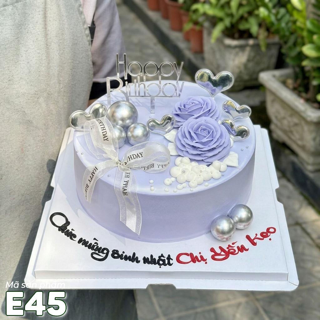 Bánh kem E45 nền màu tím nhạt với 2 đóa hoa màu tím nở rộ cùng phụ kiện tinh tế