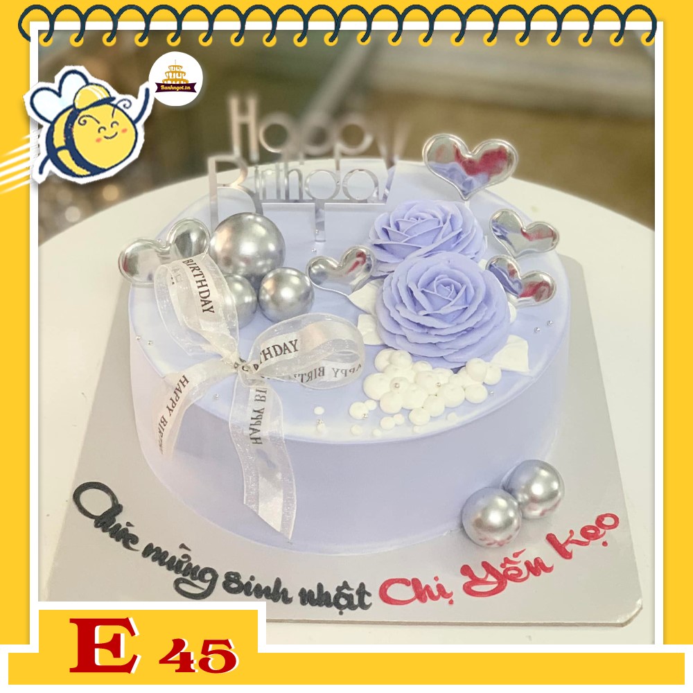Bánh kem E45 nền màu tím nhạt với 2 đóa hoa màu tím nở rộ cùng phụ kiện tinh tế