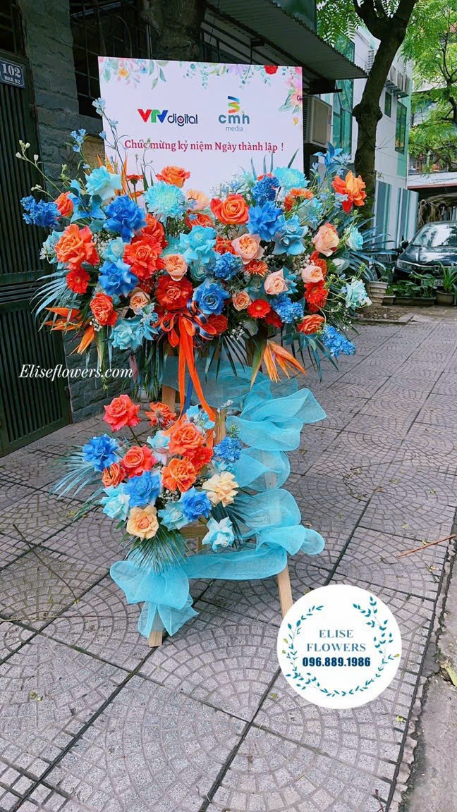 Kệ hoa khai trương xanh cam ấn tượng, hiện đại. Dịch vụ đặt hoa khai trương tại Hà Nội.