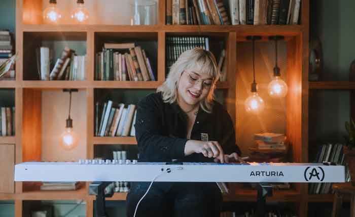 Arturia KeyLab 88 MK3 - 88 Phím hình đang được chụp miêu tả người phụ nữ đang chơi midi và đang được treo midi trên kệ đàn và midi có có màu trắng 