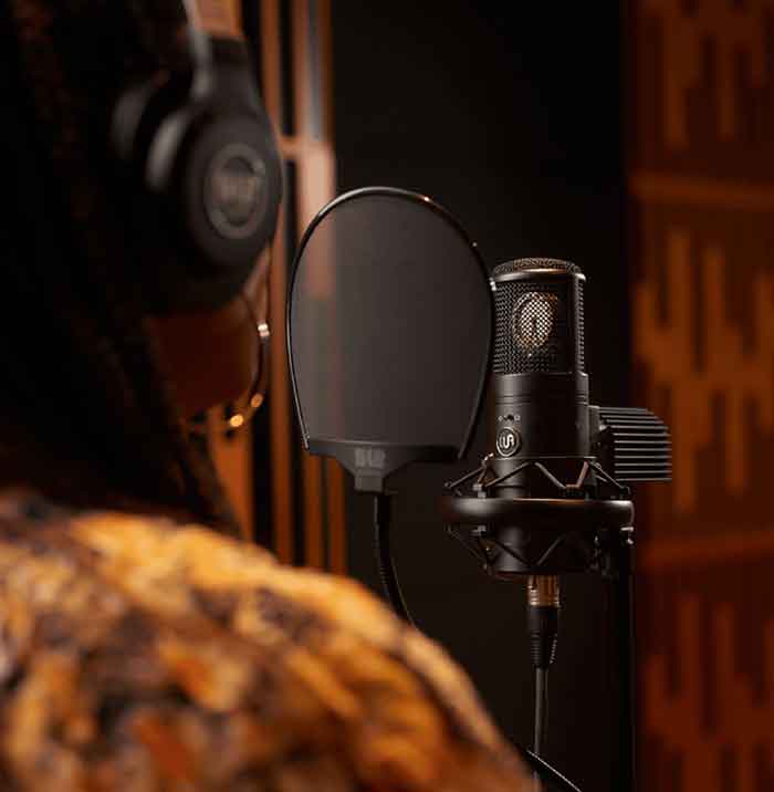 Micro Thu Âm Warm Audio WA-8000 Tube Condenser hình đang miêu tả micro đang được treo và người trong hình đang sủ dụng để thu âm 