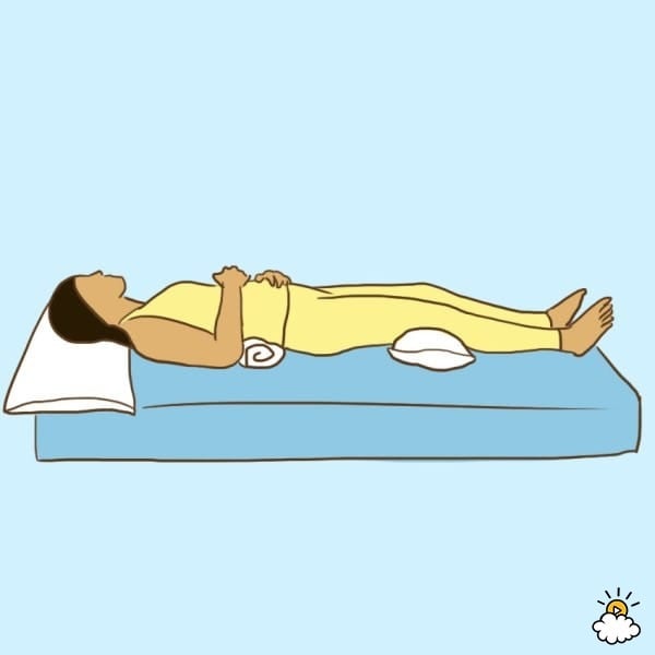 Khi đau lưng, hãy đặt một chiếc gối dưới đầu gối của bạn, đồng thời đặt một chiếc khăn cuộn dưới đường cong phần lưng của bạn