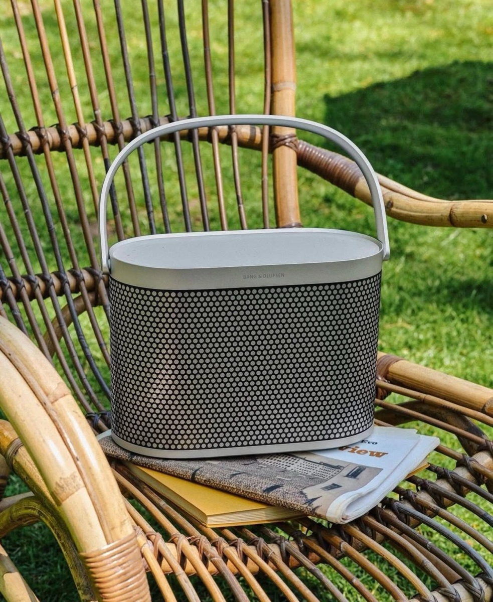 Loa B&O Beosound A5 Spaced Aluminum lifestyle trên ghế mây ngoài trời