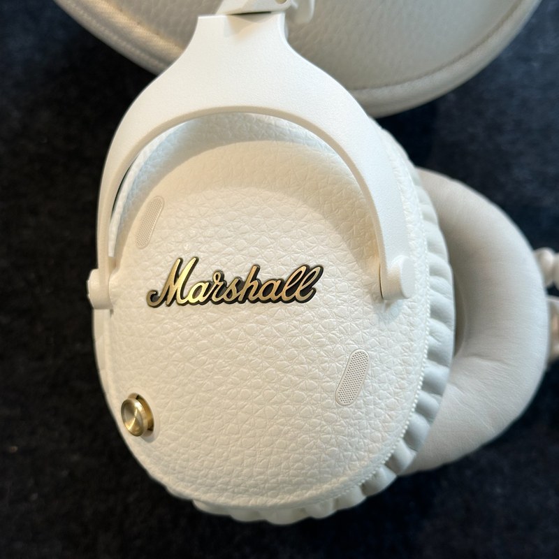 Cận cảnh logo Marshall vàng đồng trên ear cup Monitor III Cream