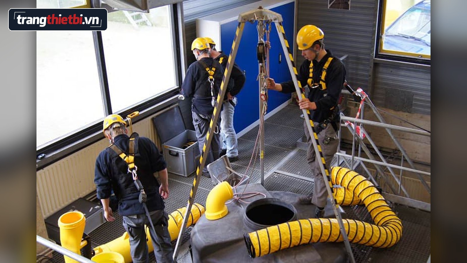 Hình ảnh công nhân mặc đai an toàn toàn thân thao tác với giá ba chân cứu hộ và hệ thống thông gió khi làm việc trong không gian hạn chế