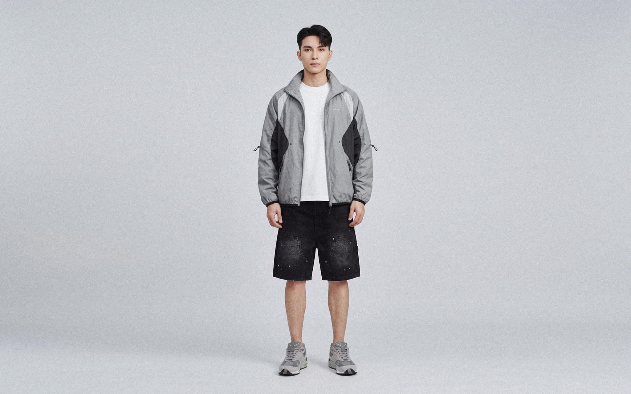 Áo khoác ghi phối quần short đen mang đến lựa chọn năng động cho phong cách nam thường ngày.
