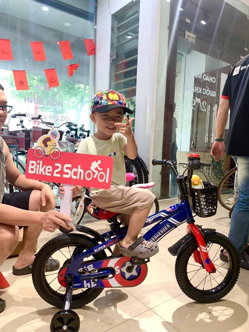 Bé trai cùng xe đạp tại cửa hàng Bike2School