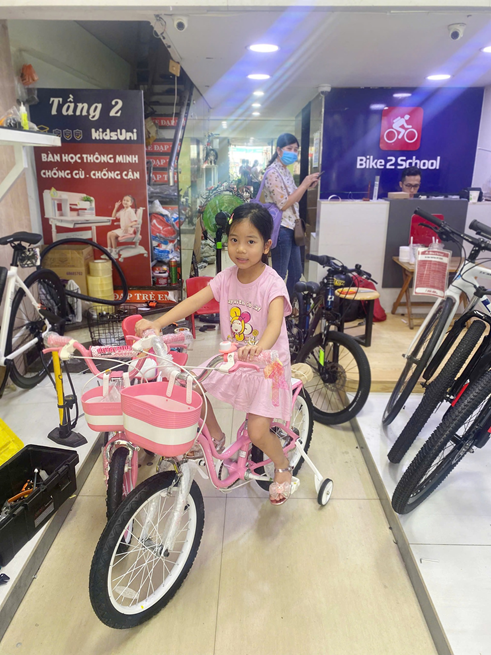 Bé gái cùng xe đạp tại cửa hàng Bike2School