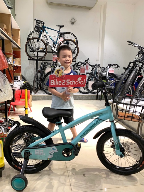 Bé trai cùng xe đạp Thống Nhất tại cửa hàng Bike2School