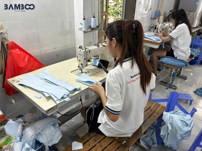 Quy trình may áo bếp trắng viền đen phối tạp dề caro được thực hiện tỉ mỉ nhằm đảm bảo sản phẩm chất lượng cao