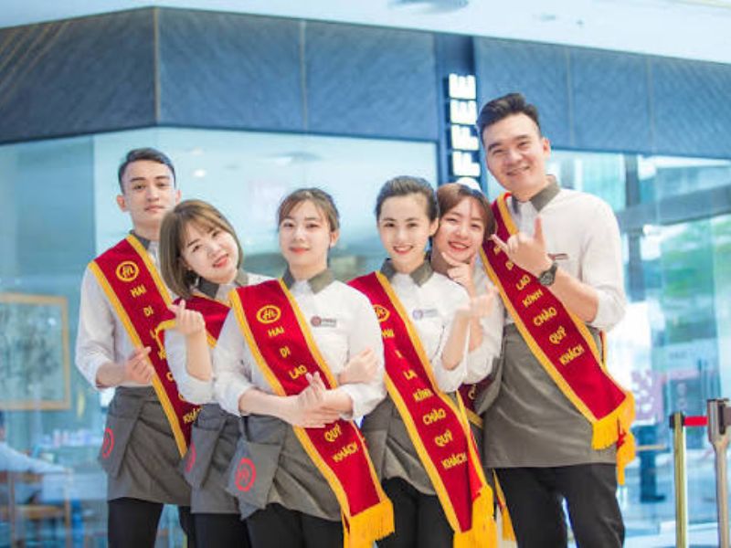 Đồng phục khu làm đẹp Haidilao gồm áo trắng phối yếm gile đỏ, tạo vẻ nhẹ nhàng, nổi bật