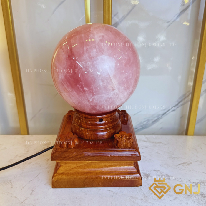 Quả Bi Cầu Đá Thạch Anh Hồng Tự Nhiên — trên đế gỗ bậc thang trước tủ kính, góc 5