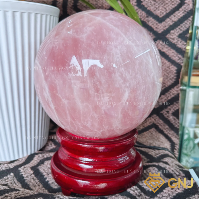 Quả Bi Cầu Đá Thạch Anh Hồng Tự Nhiên — cận cảnh trên đế gỗ đỏ, nền vải hoa văn