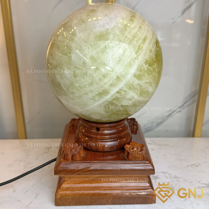 Quả Bi Cầu Đá Thạch Anh Vàng Tự Nhiên — trên đế gỗ bậc thang trước tủ kính, góc 1