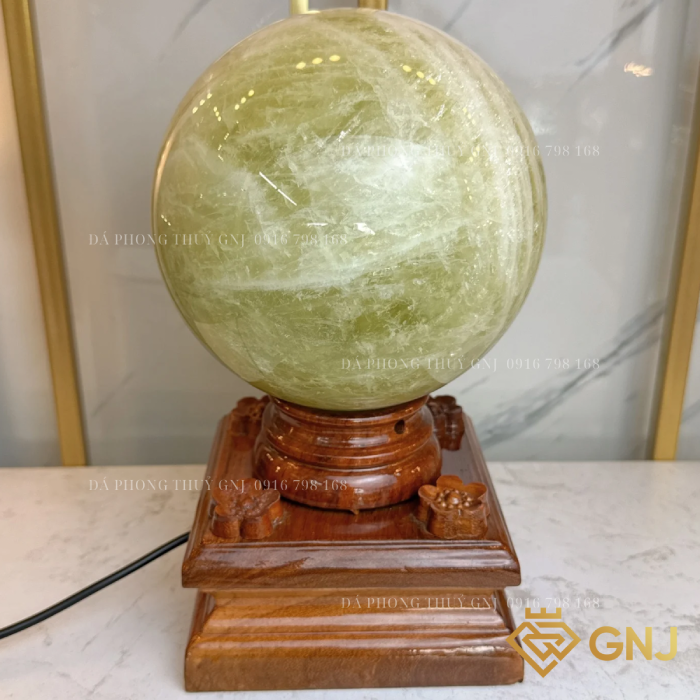 Quả Bi Cầu Đá Thạch Anh Vàng Tự Nhiên — trên đế gỗ bậc thang trước tủ kính, góc 2