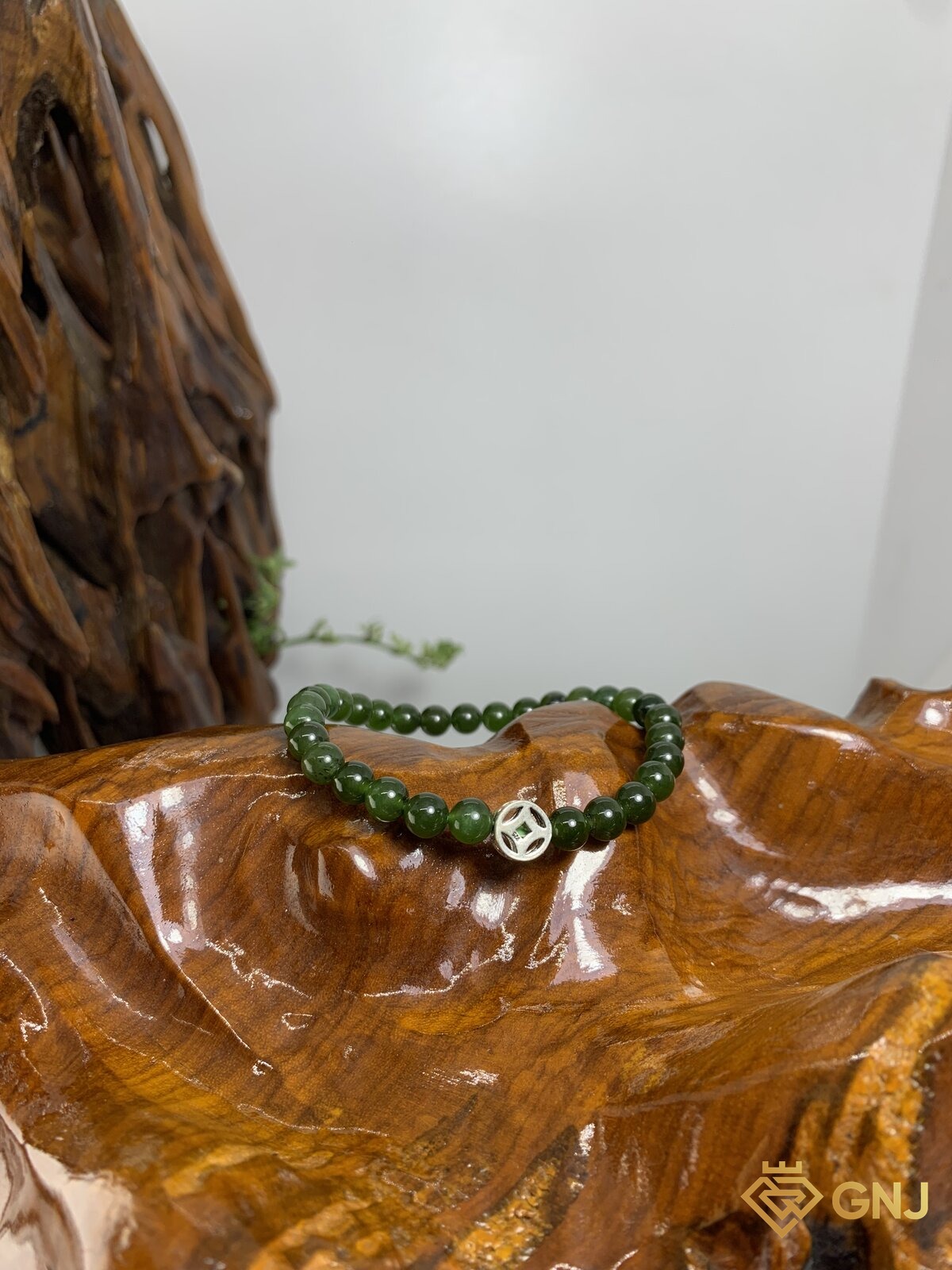 Vòng tay ngọc bích nephrite charm đồng tiền bạc S925 — ảnh chính diện trên nền gỗ, hạt xanh rêu 6,1mm