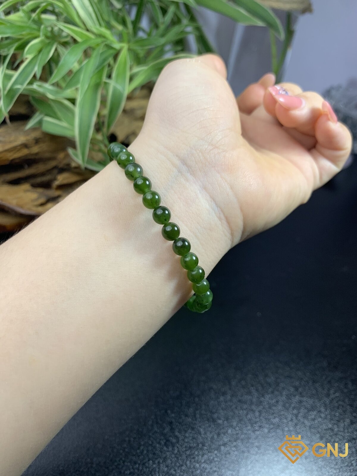 Vòng tay ngọc bích nephrite góc nghiêng trên cổ tay — độ bóng dầu đặc trưng của nephrite