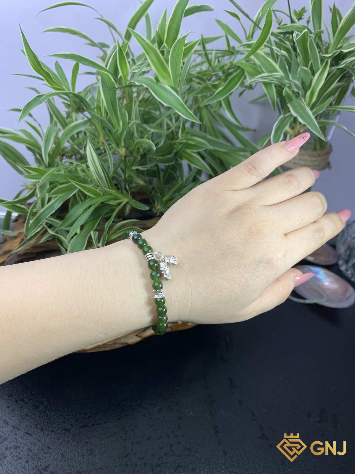 Vòng tay ngọc bích nephrite charm túi tài lộc — góc nghiêng, ngọc bích tự nhiên xanh rêu