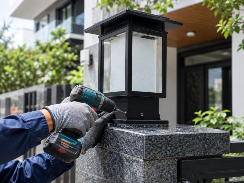 Thợ kỹ thuật siết ốc cố định chân đế lắp đặt đèn trụ cổng kiên cố
