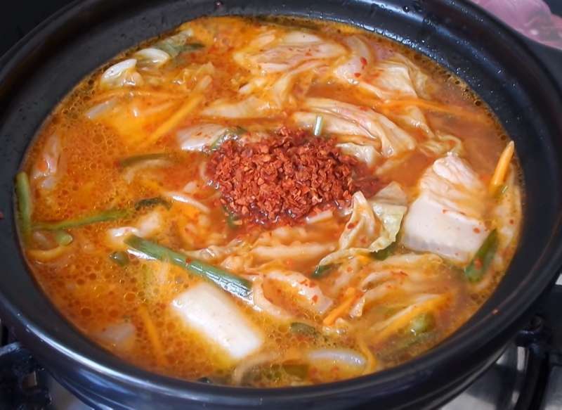 Cho thêm bột ớt Hàn Quốc vào nồi canh cho màu canh đẹp