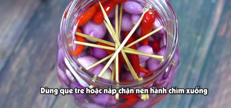 Dùng que tre hoặc nắp nén chặt hành ngập nước