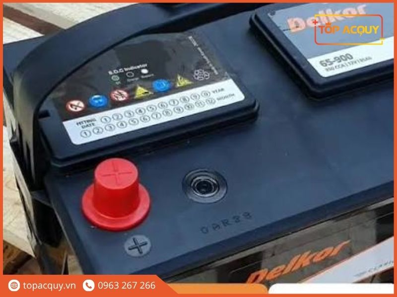 Cận cảnh cọc dương chụp bảo vệ đỏ, mắt thần chỉ thị S.O.C và bảng thông số 850CCA trên nắp bình ắc quy Delkor 65-900 12V 85Ah