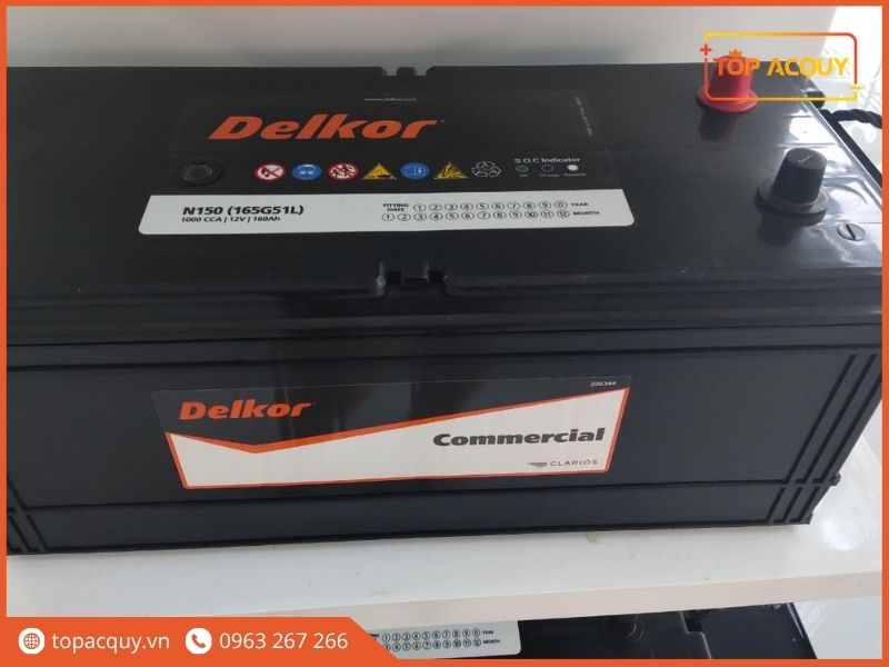 Bình ắc quy Delkor Commercial N150R (145G51R) 12V 150Ah hiển thị chi tiết nắp bảo vệ cọc đỏ, mắt thần S.O.C và tem nhãn Clarios chính hãng