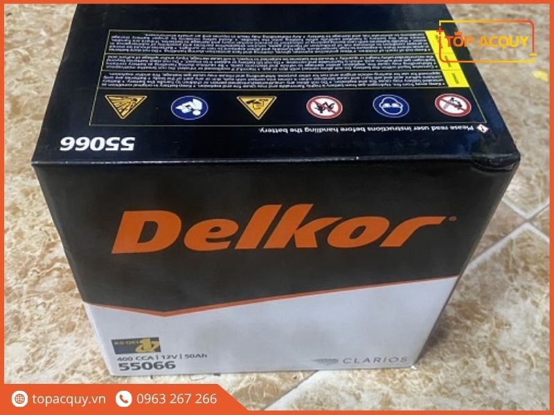 Hình ảnh vỏ hộp carton đựng ắc quy Delkor DIN50 (55066), với logo Delkor màu cam nổi bật trên nền đen