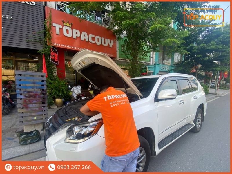 Thợ kỹ thuật TOPACQUY đang thao tác kiểm tra bình ắc quy trước cửa hàng