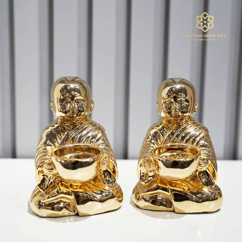 Tượng Chú Tiểu mạ vàng ngồi thiền bên ngọn nến, mang lại cảm giác bình an, tĩnh lặng và sự giác ngộ trong không gian sống