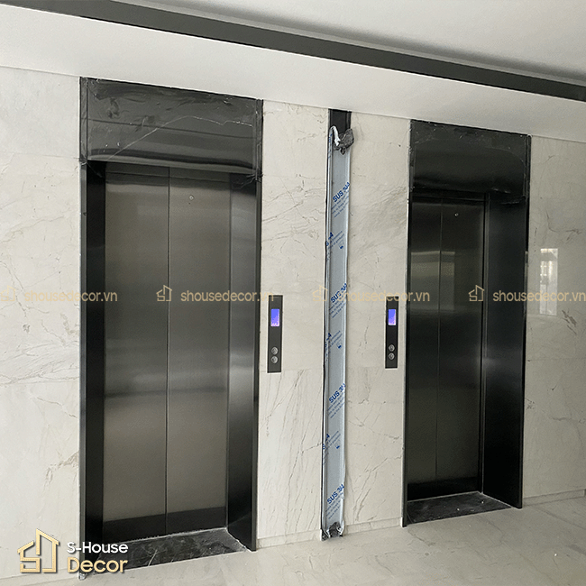 Hạng mục trang trí inox thang máy tại HEAC Building với khung bao inox 304 xước đen bản rộng, tạo điểm nhấn hiện đại cho khu vực cửa tầng.