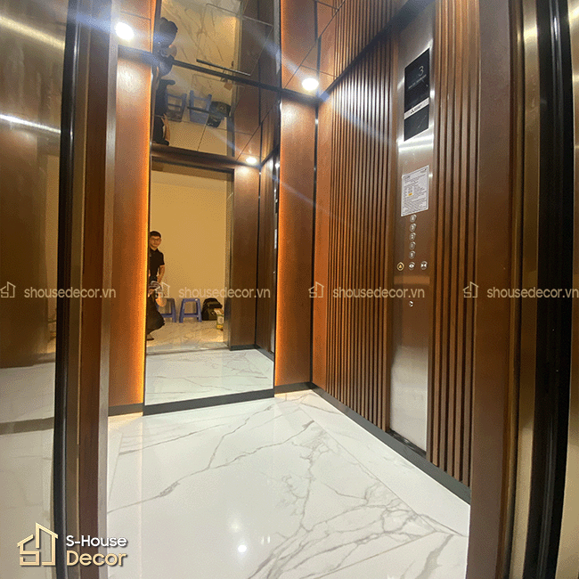 Không gian cabin thang máy được trang trí bằng inox gương kết hợp gỗ sồi, mang lại cảm giác sang trọng và hiện đại.