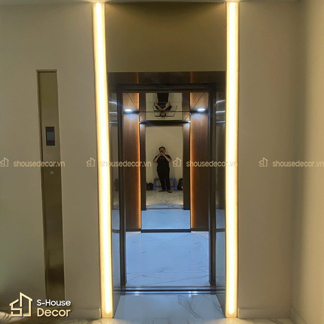 Khu vực cửa thang máy tại công trình 15C Trần Khánh Dư sau khi hoàn thiện khung bao inox xước vàng champagne bản rộng.