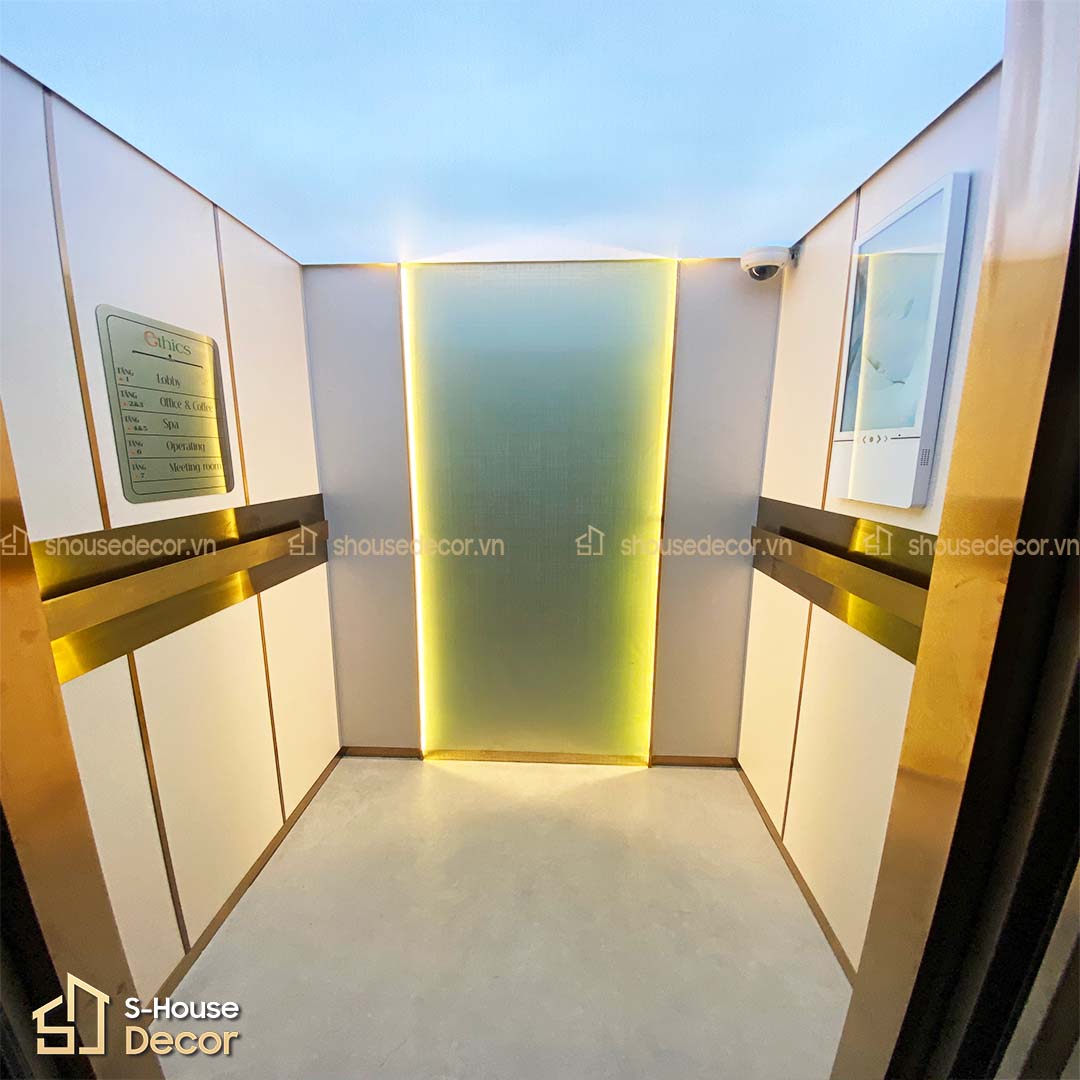 Góc nhìn cabin thang máy hoàn thiện sau khi phối inox, tranh, laminate và tay vịn mạ vàng.