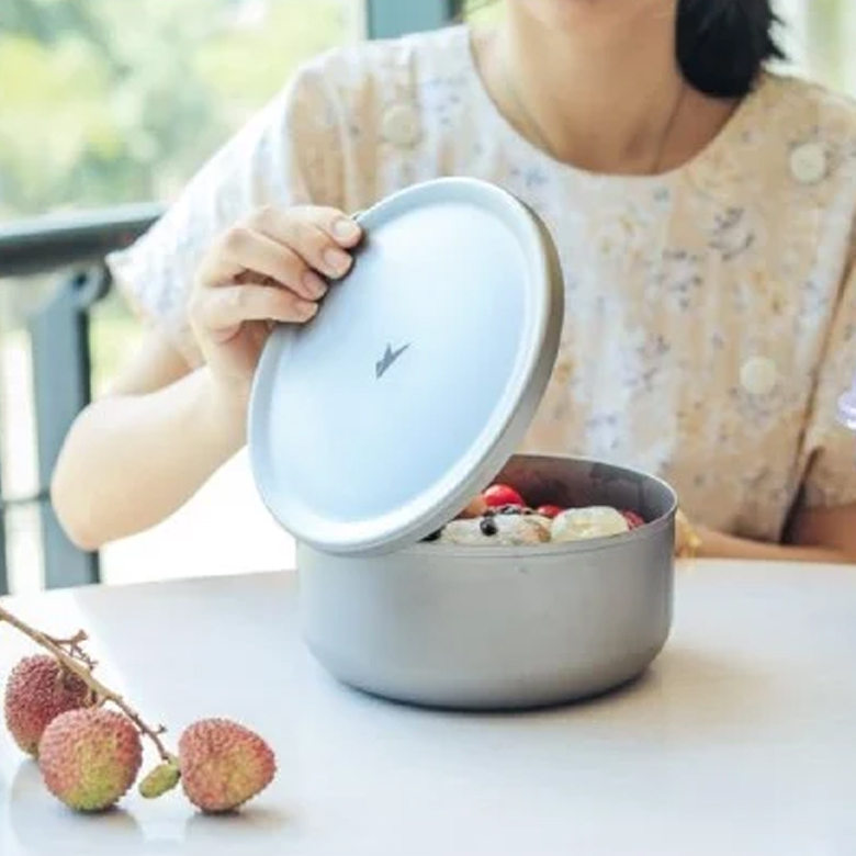 Cô gái mở nắp nồi titanium đựng trái cây trên bàn
