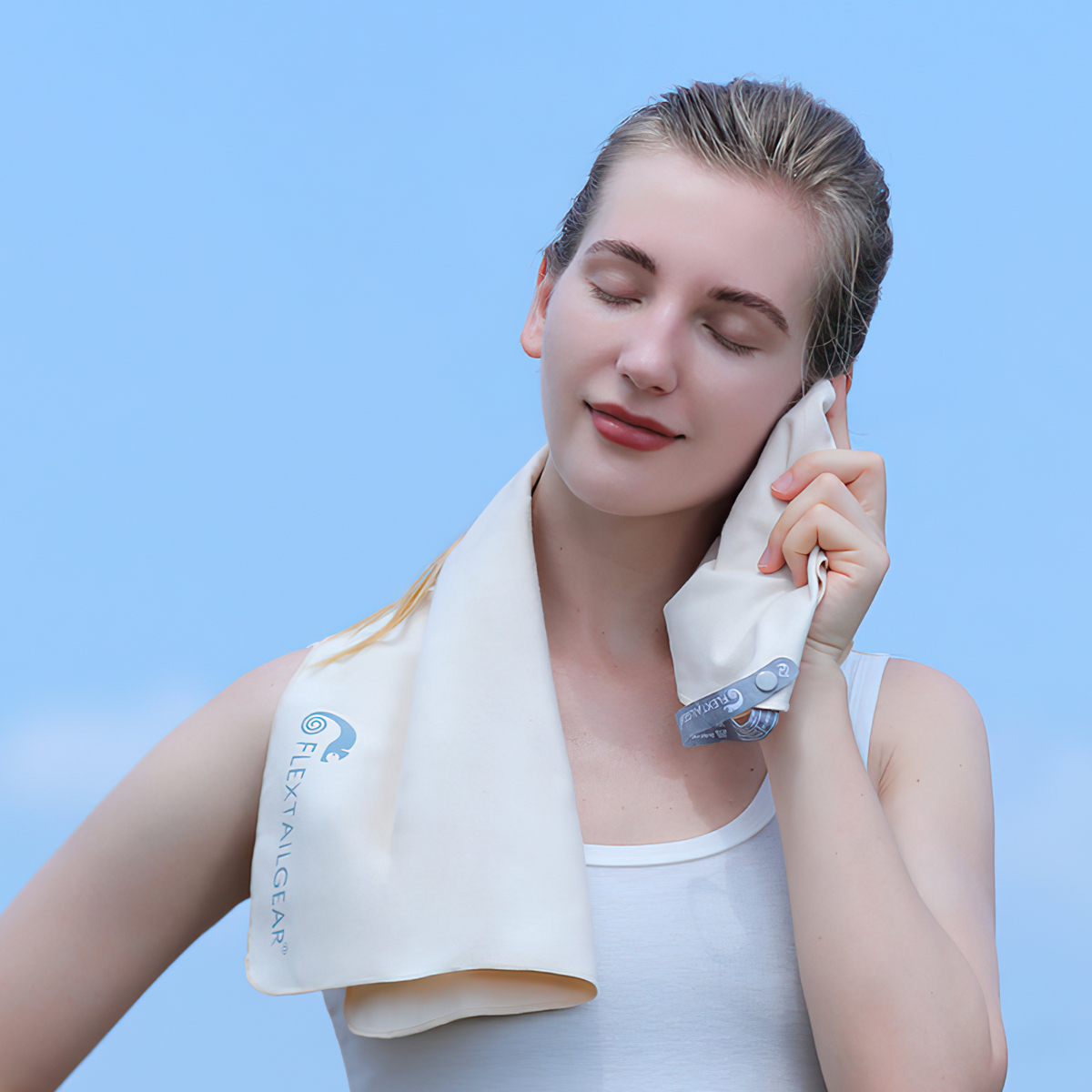 Khăn mặt đa năng Flextail Cozy Towel màu be quàng quanh cổ một phụ nữ đang áp lên má