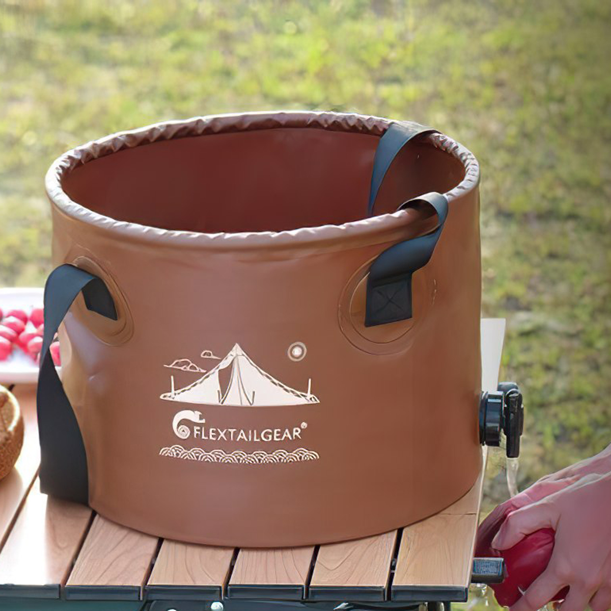 Xô nước gấp gọn Flextail Flex Bucket đặt trên bàn cắm trại ngoài trời cùng vài quả cà chua