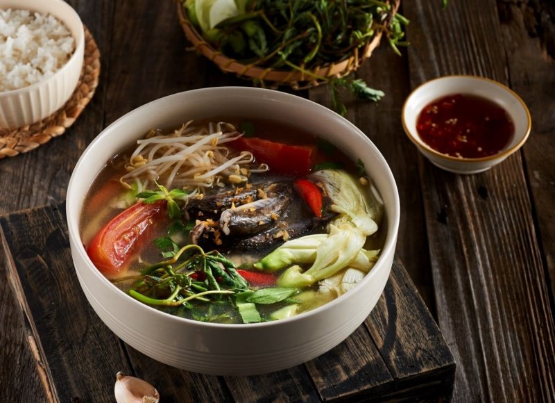 Thả rau thơm, đậu bắp và cà chua vào nồi canh cá lăng