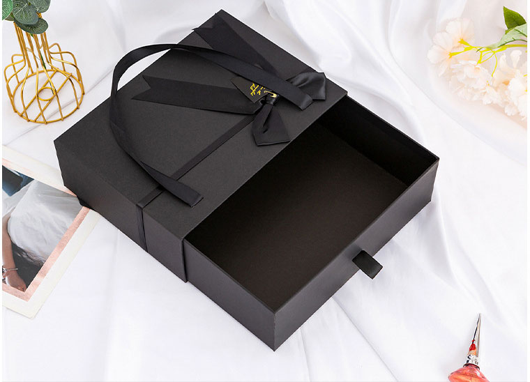 Hộp giấy màu đen có quai túi xách gắn nơ đựng quà tặng