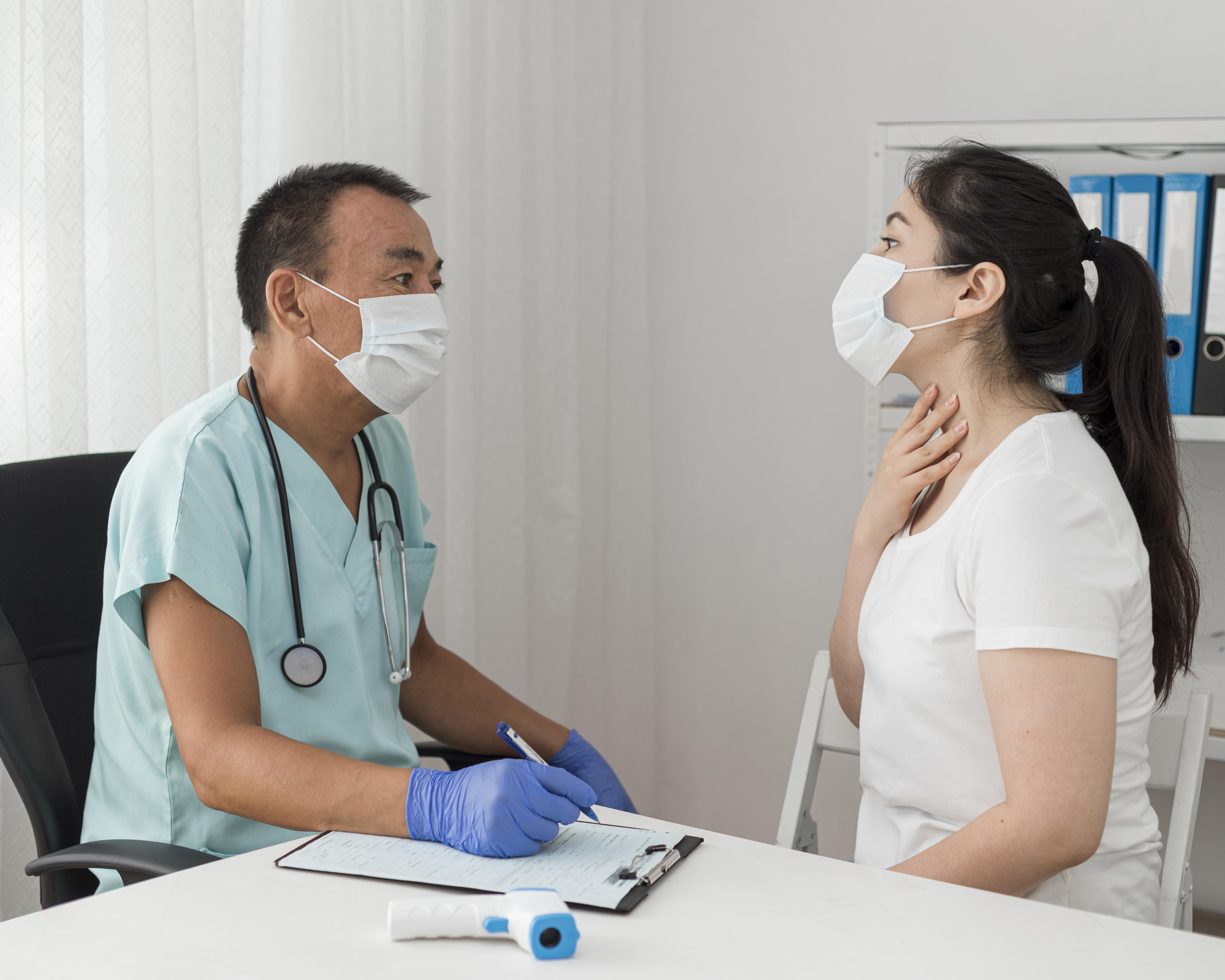 Nhân viên y tế ghi nhận triệu chứng của người bệnh đeo khẩu trang tại cơ sở khám chữa bệnh