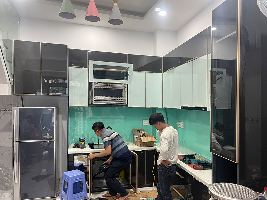 Tủ bếp hiện đại chữ L, khung inox 304 sơn tĩnh điện, cánh kính sơn màu viền nhôm, mặt đá marble vân mây, ốp tường kính cường lực - Thi công