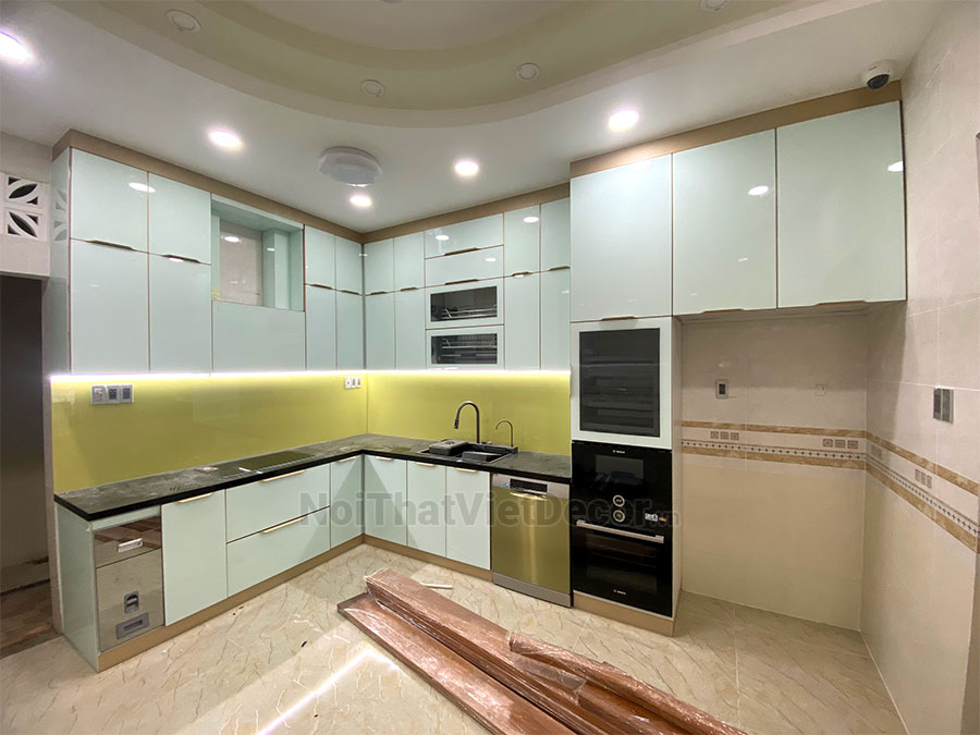 Tủ bếp hiện đại chữ L, khung inox 304 sơn tĩnh điện, cánh kính sơn màu viền nhôm, mặt bếp đá tự nhiên kim sa đen, ốp tường kính cường lực 8mm - Hoàn thiện