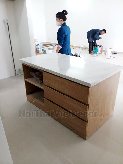 Tủ bếp hiện đại chữ I có đảo, gỗ công nghiệp MDF chống ẩm phủ melamine Thanh Thùy, mặt đá tự nhiên kim sa đen, ốp tường kính cường lực 8mm sơn màu - Hình hoàn thiện