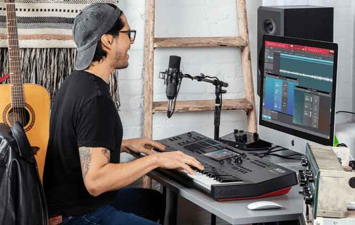 Đàn Akai Professional MPC Key 61 đàn đang được đặt trên bàn và kết nối với thiết bị khác để sản xuất âm nhạc 